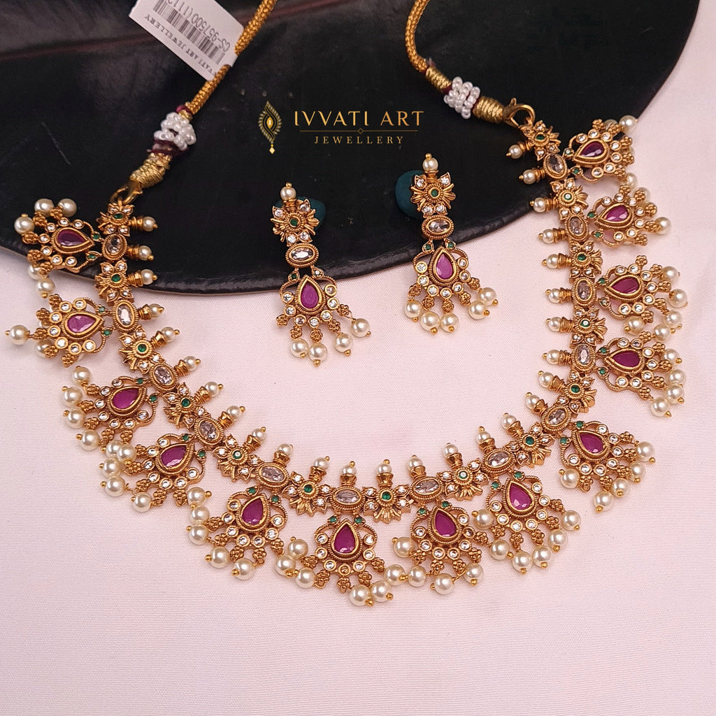 Gold finish temple-style necklace with pink kundan, green stones, and pearl drops with matching earrings

