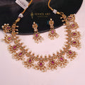 Gold finish temple-style necklace with pink kundan, green stones, and pearl drops with matching earrings

