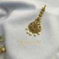 Antique gold floral maang tikka with ruby-emerald stones and pearl hangings – handcrafted by Ivvati Art Jewellery.
