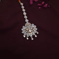 Traditional Kundan maangtikka displayed on velvet background with detailed floral design