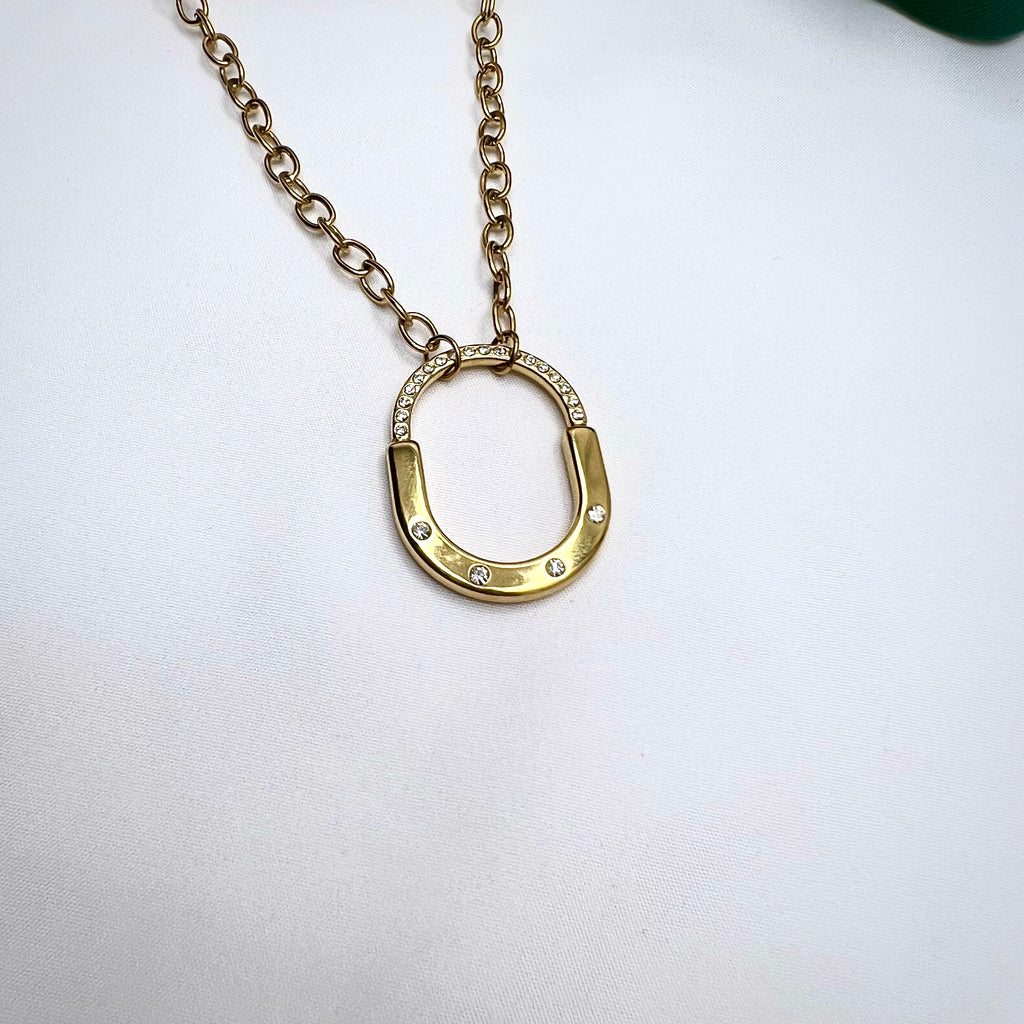 Chunky gold chain necklace with a U-shaped CZ studded pendant on white background


